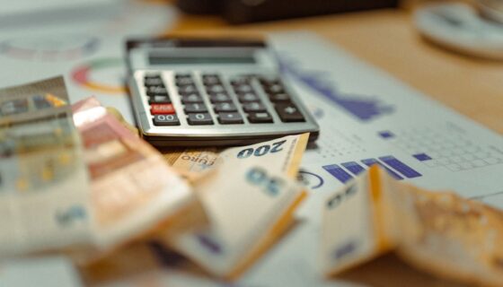 Euro banknotes and calculator on financial documents, focusing on business budget planning.