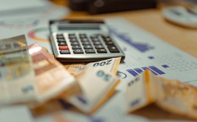 Euro banknotes and calculator on financial documents, focusing on business budget planning.